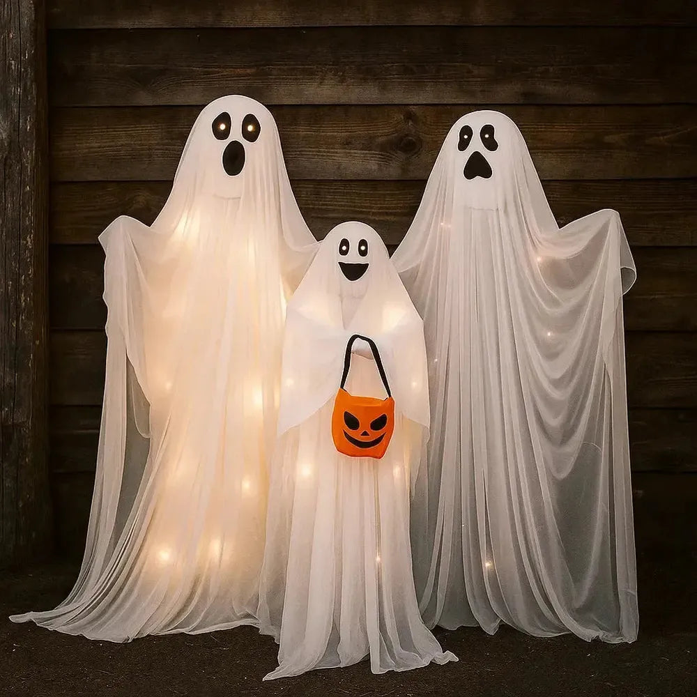 Three ghost decorations with string lights against a wooden wall.